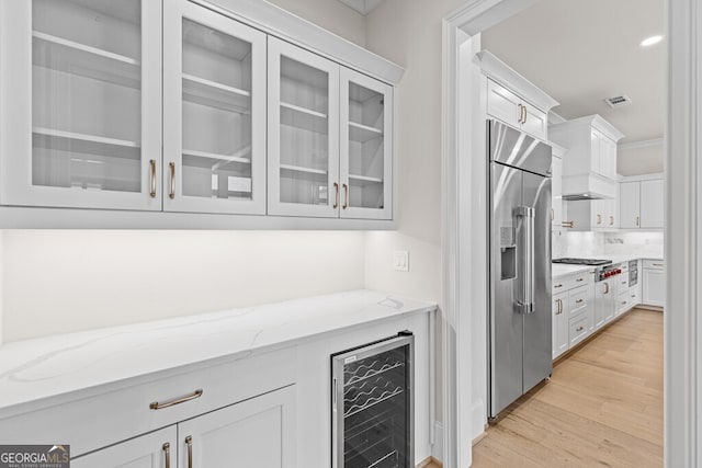 2824 Cork St, Braselton, GA 30517 - bar with appliances with stainless steel finishes, beverage cooler, tasteful backsplash, light wood-type flooring, and custom exhaust hood