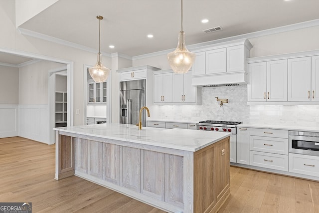 2824 Cork St, Braselton, GA 30517 - kitchen with appliances with stainless steel finishes, premium range hood, crown molding, light wood-style floors, and an island with sink