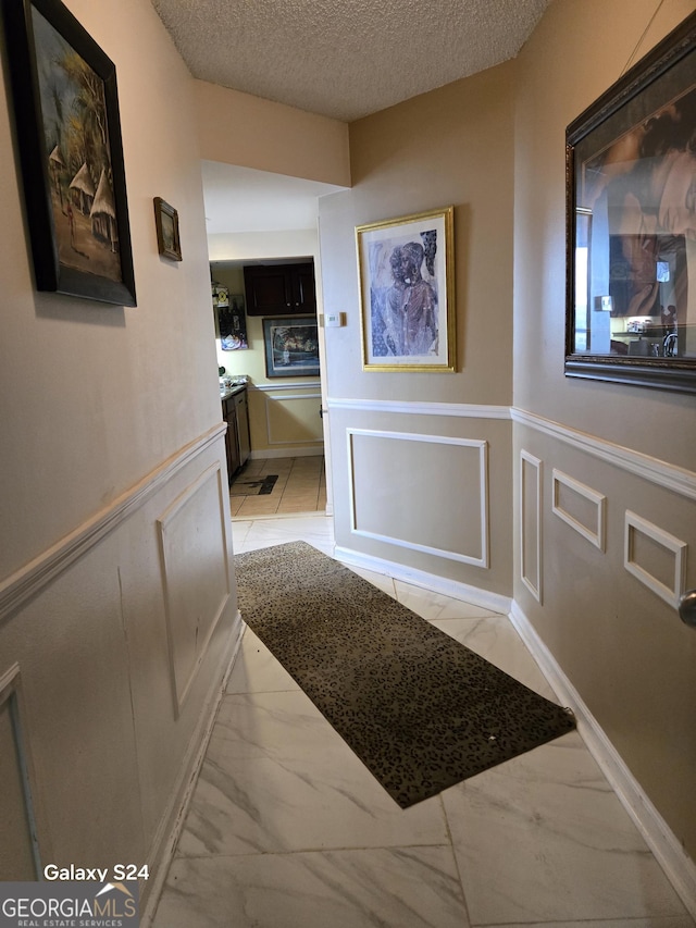 1280 W Peachtree St NW Apt 2606, Atlanta, GA 30309 - hall with a textured ceiling, marble finish floor, a decorative wall, and a wainscoted wall