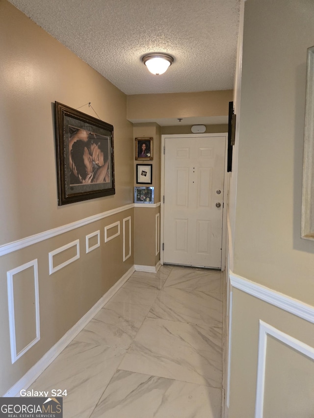 1280 W Peachtree St NW Apt 2606, Atlanta, GA 30309 - corridor with a textured ceiling, marble finish floor, and wainscoting