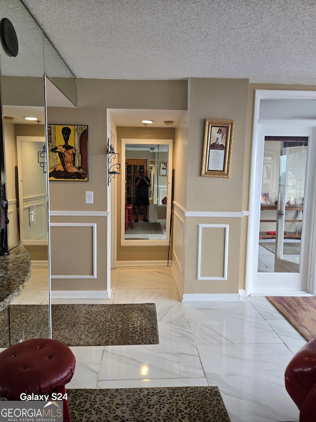1280 W Peachtree St NW Apt 2606, Atlanta, GA 30309 - interior space with marble finish floor, wainscoting, a textured ceiling, and a decorative wall