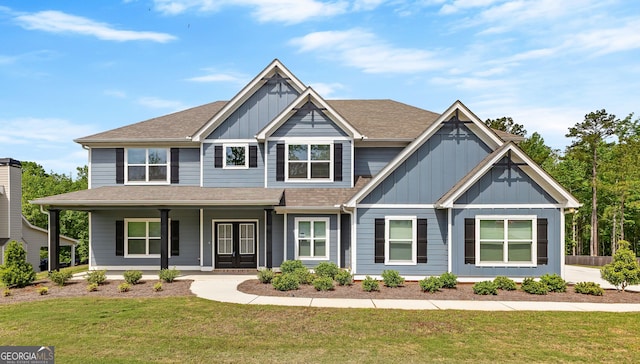 craftsman inspired home featuring board and batten siding, covered porch, a shingled roof, and a front lawn