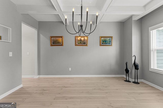 unfurnished dining area with coffered ceiling, light wood finished floors, a chandelier, and a wealth of natural light
