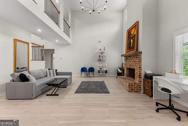 living room with light wood-style floors, baseboards, an inviting chandelier, and a towering ceiling