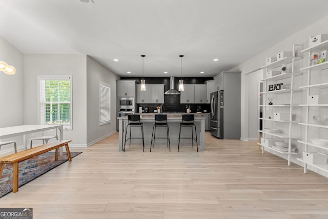 kitchen featuring a kitchen island, appliances with stainless steel finishes, light wood-type flooring, and a kitchen bar
