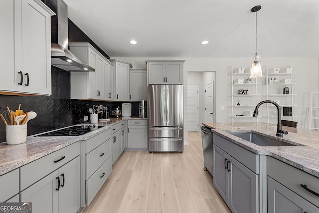 kitchen with wall chimney range hood, stainless steel appliances, gray cabinets, and a sink