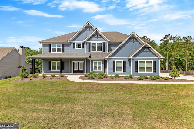 craftsman house with roof with shingles, board and batten siding, a porch, and a front yard