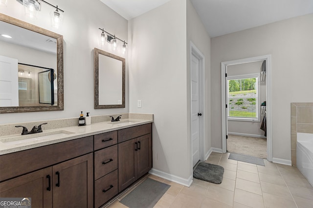 bathroom with a garden tub, a sink, baseboards, and tile patterned floors