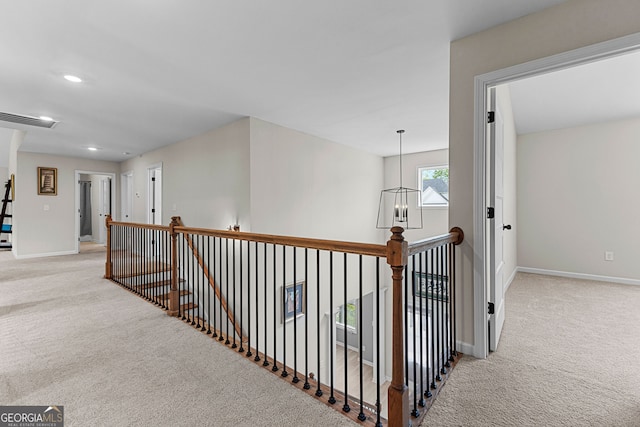 hallway with baseboards, carpet, and an upstairs landing