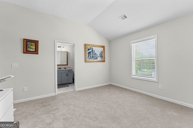 empty room featuring baseboards, light carpet, vaulted ceiling, and visible vents