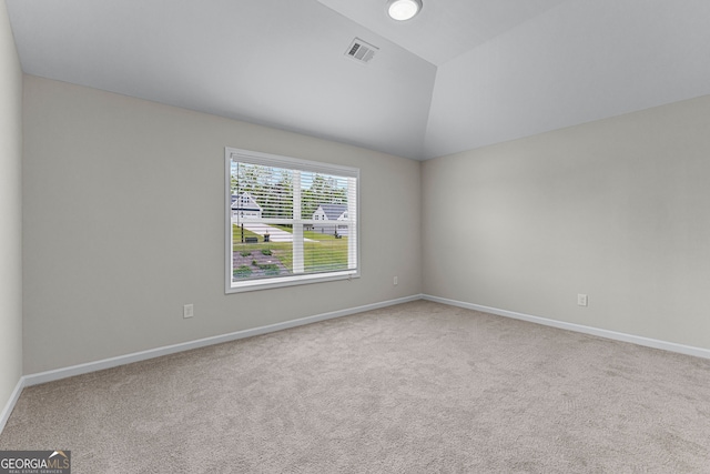 carpeted spare room featuring baseboards, lofted ceiling, and visible vents