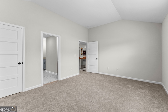 unfurnished bedroom featuring carpet floors, connected bathroom, baseboards, and vaulted ceiling