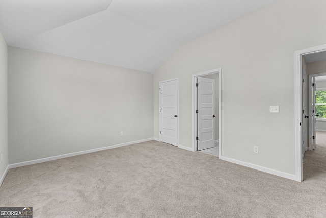unfurnished bedroom with carpet floors, baseboards, and lofted ceiling