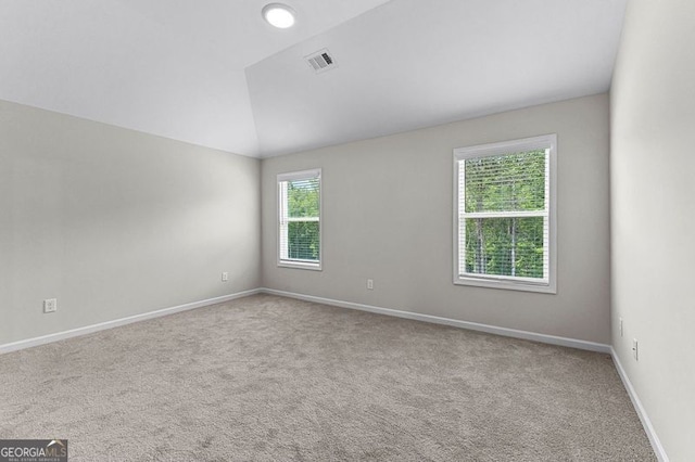 carpeted empty room featuring baseboards, lofted ceiling, and visible vents