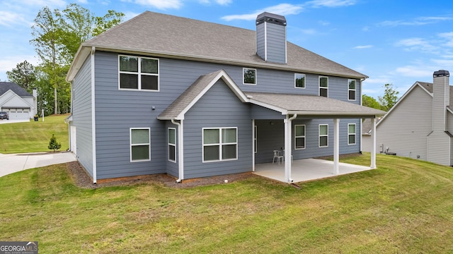 back of house with a yard, roof with shingles, a chimney, and a patio area