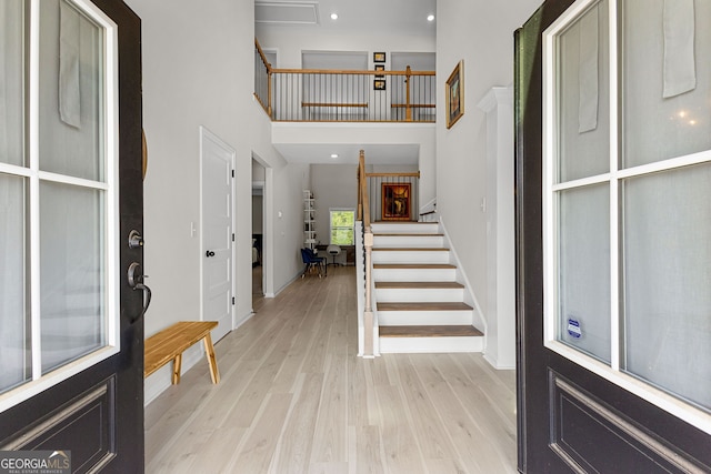 foyer with baseboards, a high ceiling, stairway, recessed lighting, and light wood-style flooring