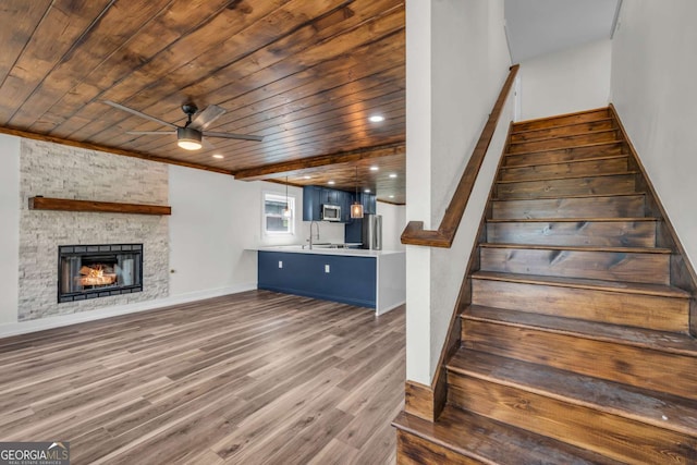 233 Bradshaw Rd, Hiawassee, GA 30546 - stairway featuring ceiling fan, a stone fireplace, baseboards, wooden ceiling, and wood finished floors