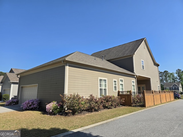 view of property exterior featuring an attached garage, fence, and concrete driveway