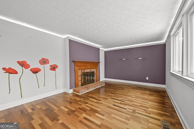 4608 Rosemear Ct, Norcross, GA 30093 - unfurnished living room with a brick fireplace, a textured ceiling, baseboards, wood finished floors, and visible vents