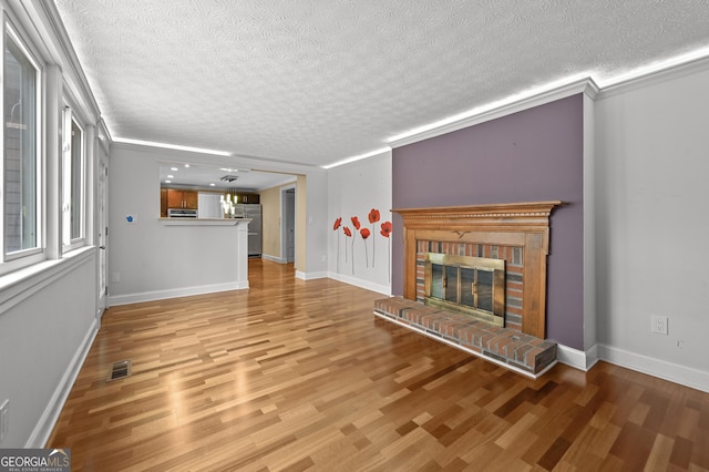 4608 Rosemear Ct, Norcross, GA 30093 - unfurnished living room with a textured ceiling, visible vents, a brick fireplace, wood finished floors, and baseboards
