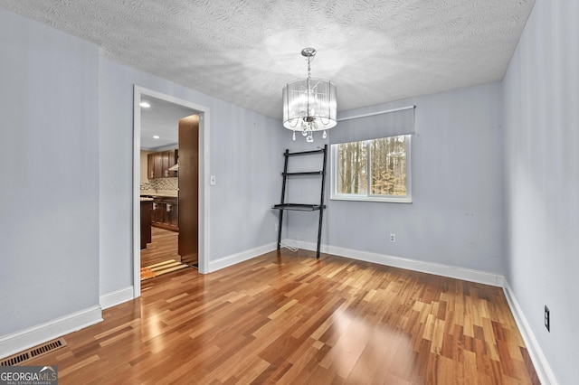 4608 Rosemear Ct, Norcross, GA 30093 - unfurnished dining area featuring visible vents, a textured ceiling, wood finished floors, and a notable chandelier