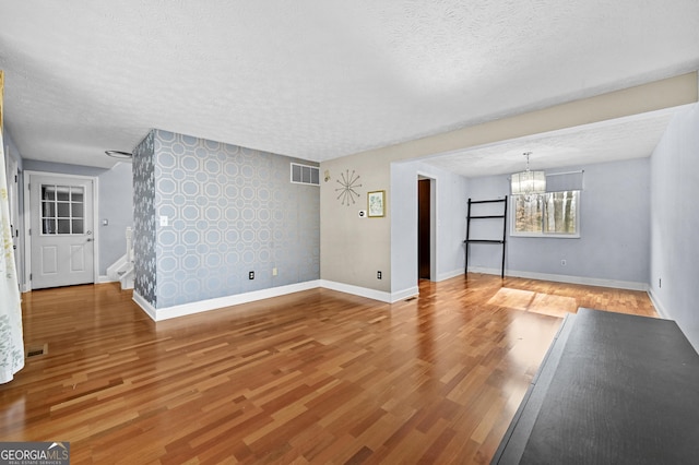 4608 Rosemear Ct, Norcross, GA 30093 - unfurnished living room with a textured ceiling, visible vents, wood finished floors, baseboards, and a chandelier