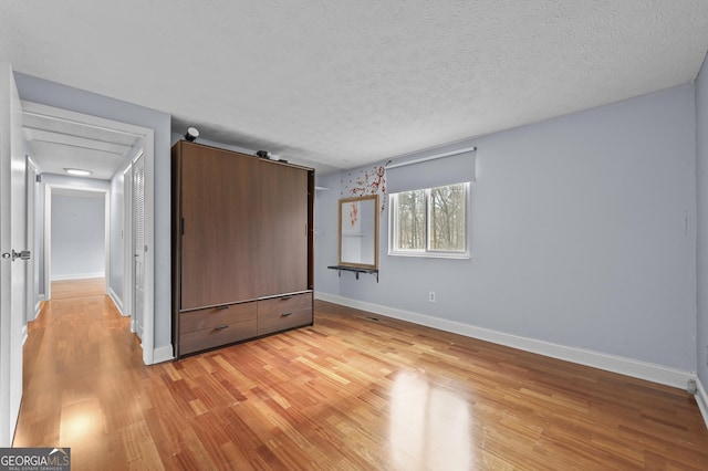 4608 Rosemear Ct, Norcross, GA 30093 - unfurnished bedroom with baseboards, a textured ceiling, and light wood-style flooring