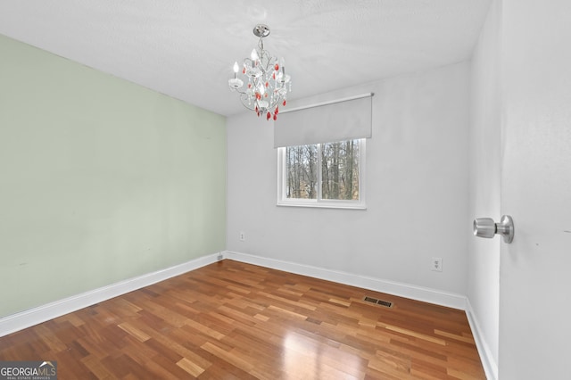 4608 Rosemear Ct, Norcross, GA 30093 - empty room featuring baseboards, a chandelier, wood finished floors, and visible vents