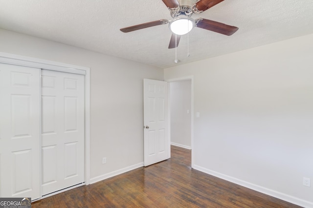 unfurnished bedroom with a closet, a textured ceiling, wood finished floors, and baseboards