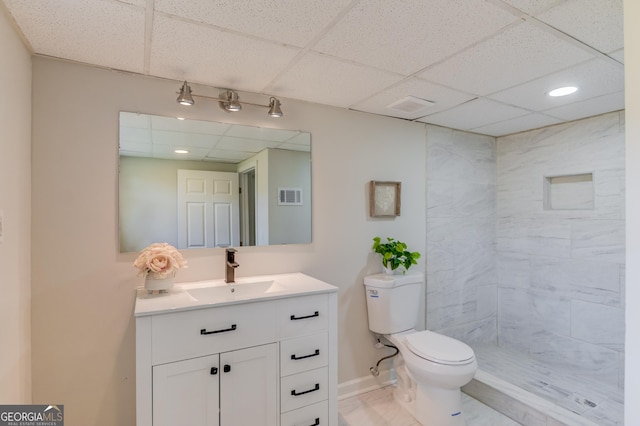 bathroom with toilet, visible vents, vanity, and a paneled ceiling