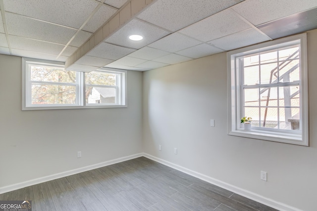 below grade area with a paneled ceiling, a wealth of natural light, and baseboards