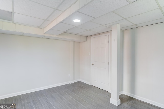 finished basement with a drop ceiling, wood finished floors, and baseboards