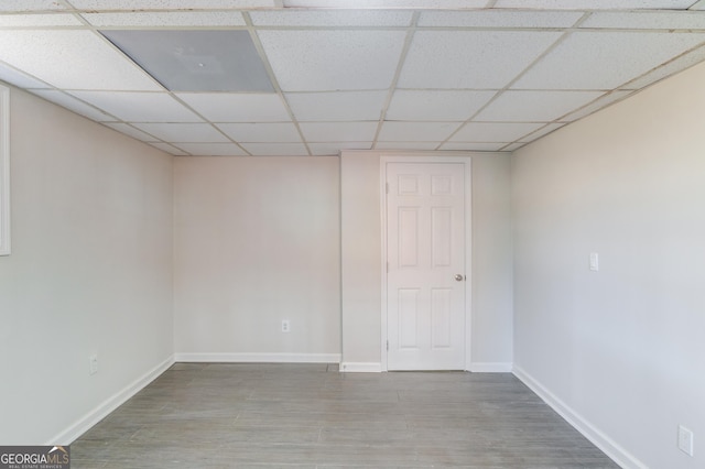 interior space featuring baseboards, a paneled ceiling, and wood finished floors