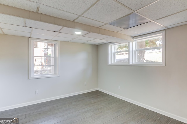 empty room with a paneled ceiling, baseboards, and wood finished floors