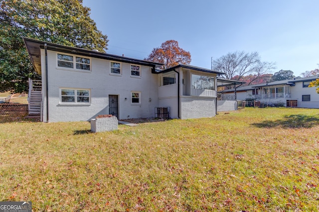 rear view of property featuring brick siding, fence, and a lawn
