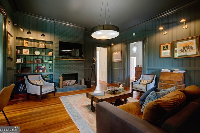 living room featuring crown molding, a brick fireplace, and wood finished floors