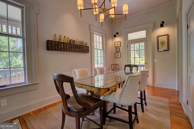 dining area featuring crown molding, light wood-style flooring, baseboards, and an inviting chandelier