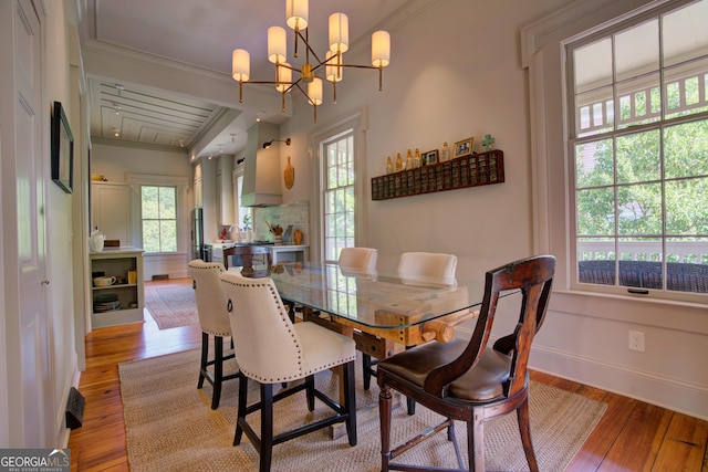 dining room with crown molding, baseboards, an inviting chandelier, and light wood-style floors
