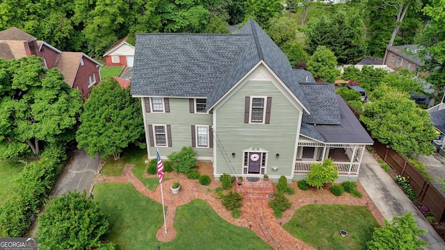 view of front of home featuring covered porch, a shingled roof, and a front yard