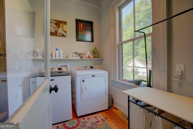 clothes washing area featuring separate washer and dryer, laundry area, visible vents, and light wood-style flooring