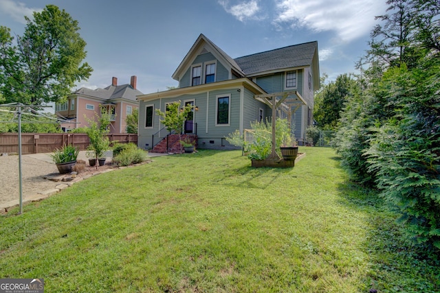 rear view of house featuring fence, a yard, and crawl space