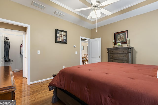 bedroom with baseboards, visible vents, a tray ceiling, and light wood-type flooring