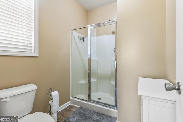 bathroom with baseboards, tile patterned floors, a stall shower, and toilet
