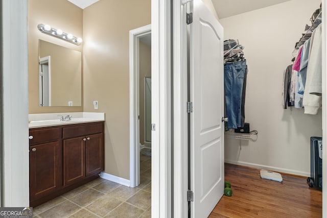 bathroom featuring baseboards, a spacious closet, and vanity