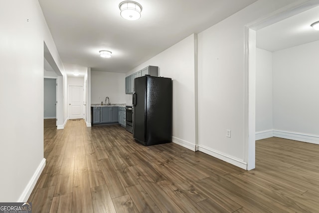 kitchen featuring dark wood-style flooring, light countertops, gray cabinets, freestanding refrigerator, and baseboards