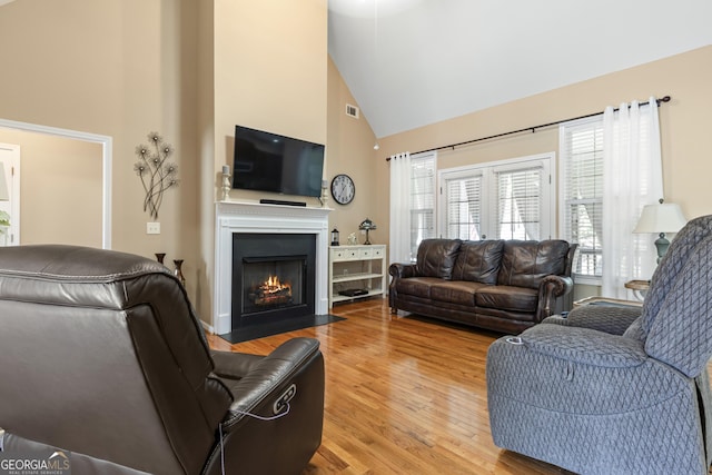 living room with visible vents, light wood-style flooring, a healthy amount of sunlight, and high vaulted ceiling