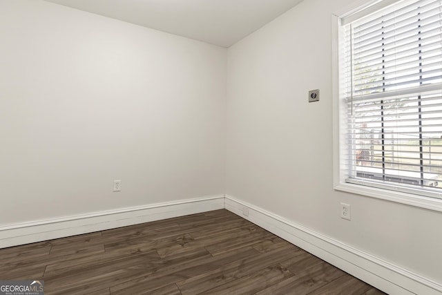 unfurnished room with baseboards and dark wood finished floors