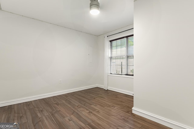 unfurnished room with baseboards, a ceiling fan, wood finished floors, and electric panel