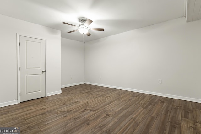 spare room with baseboards, a ceiling fan, and dark wood-style flooring