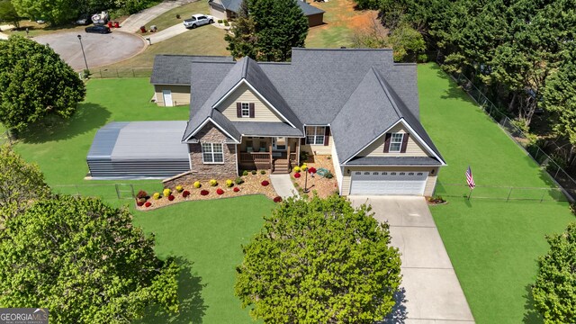 view of front of property featuring a garage, a front yard, stone siding, and concrete driveway